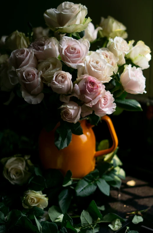 a yellow watering pitcher filled with flowers next to a green plant