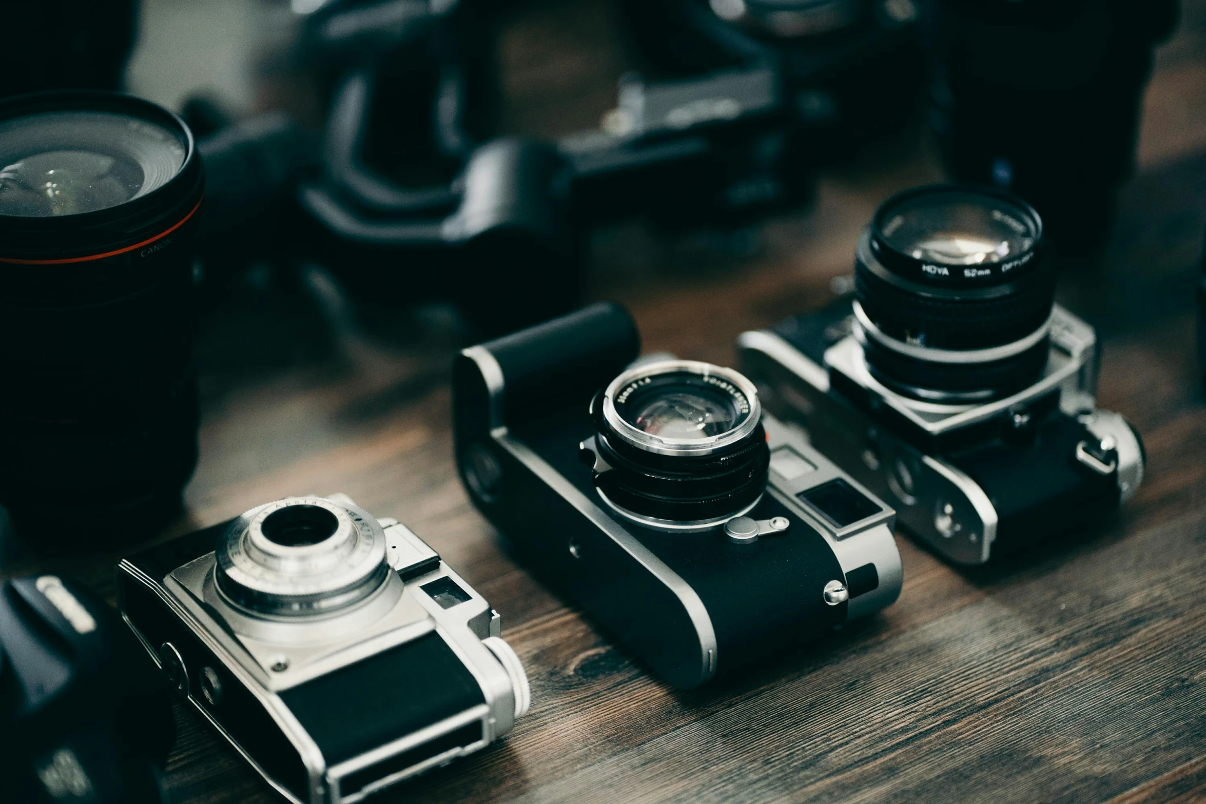 three cameras are set on a wood floor