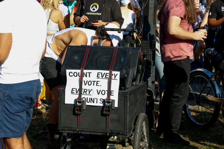 several people standing around and gathered around a man in an antique buggy