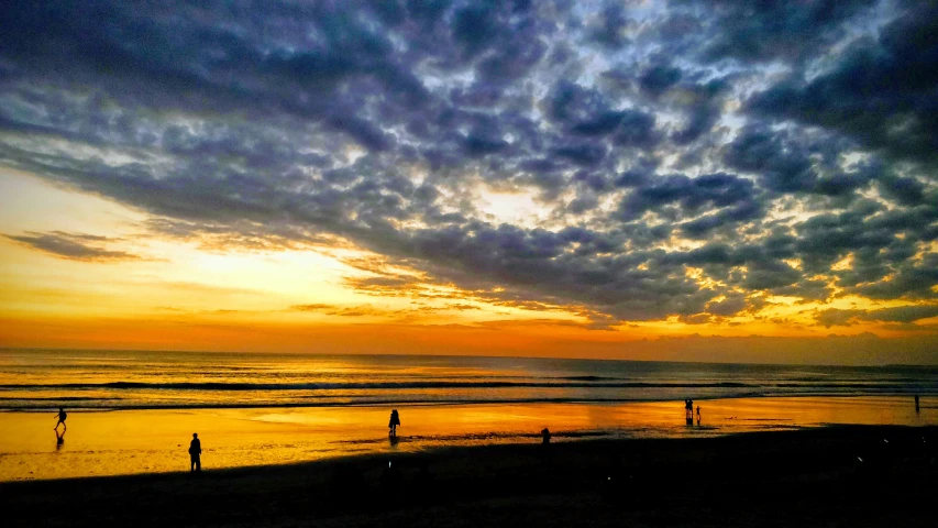 an orange and purple sky at sunset at a beach