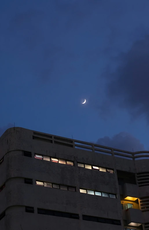 the moon is seen near some buildings and a sky