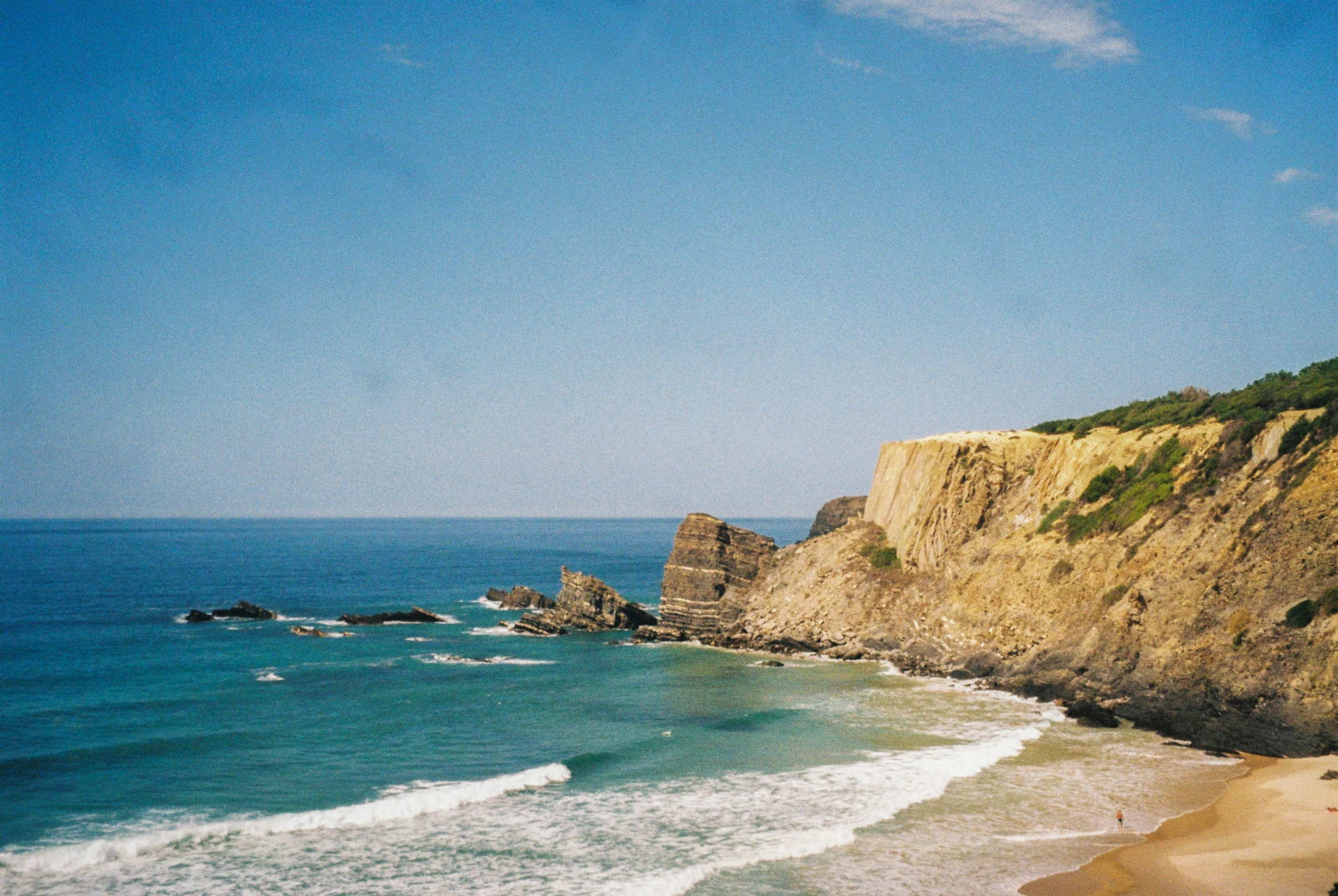 a beach on the coast with the ocean in front of it