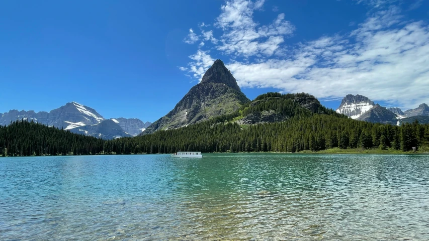 the mountain peaks are above the water with some small boats