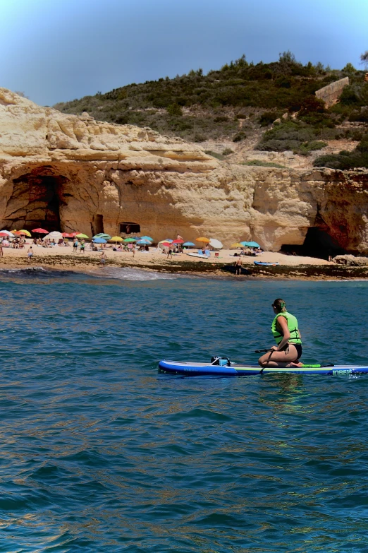 a person in a green outfit paddling on a blue kayak