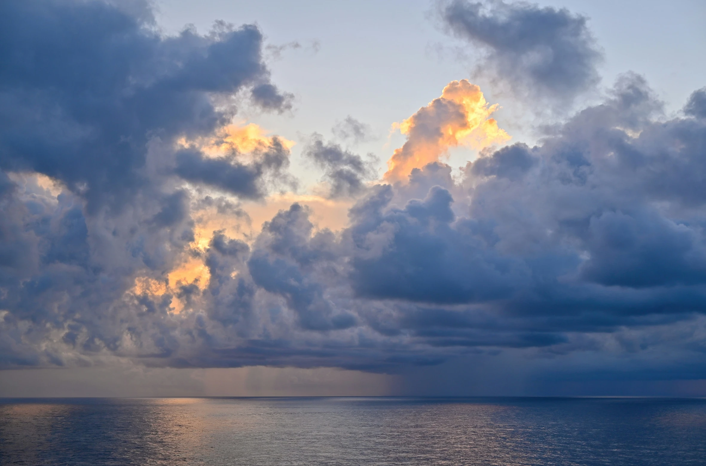 a view of an ocean with clouds at sunset