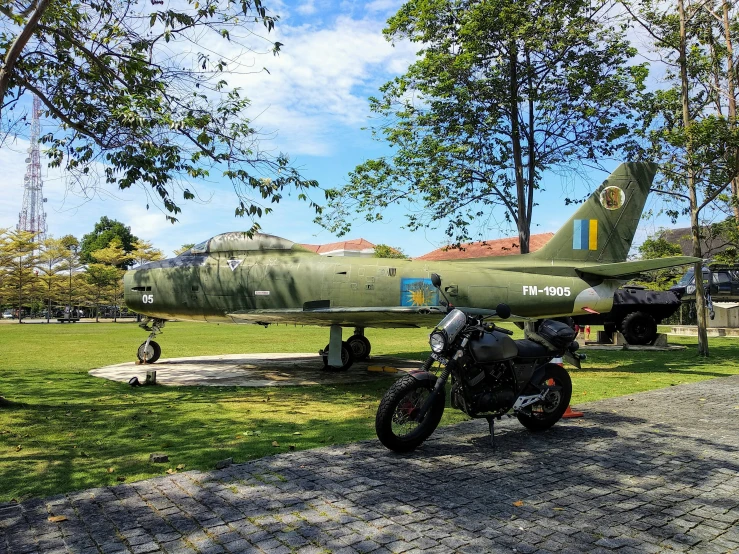 a jet and a motorcycle sitting next to each other in a park