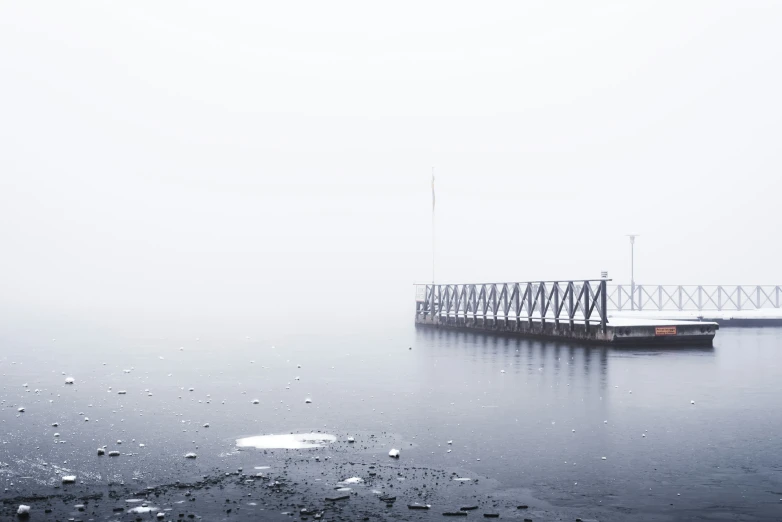 a long pier covered in ice near a large body of water