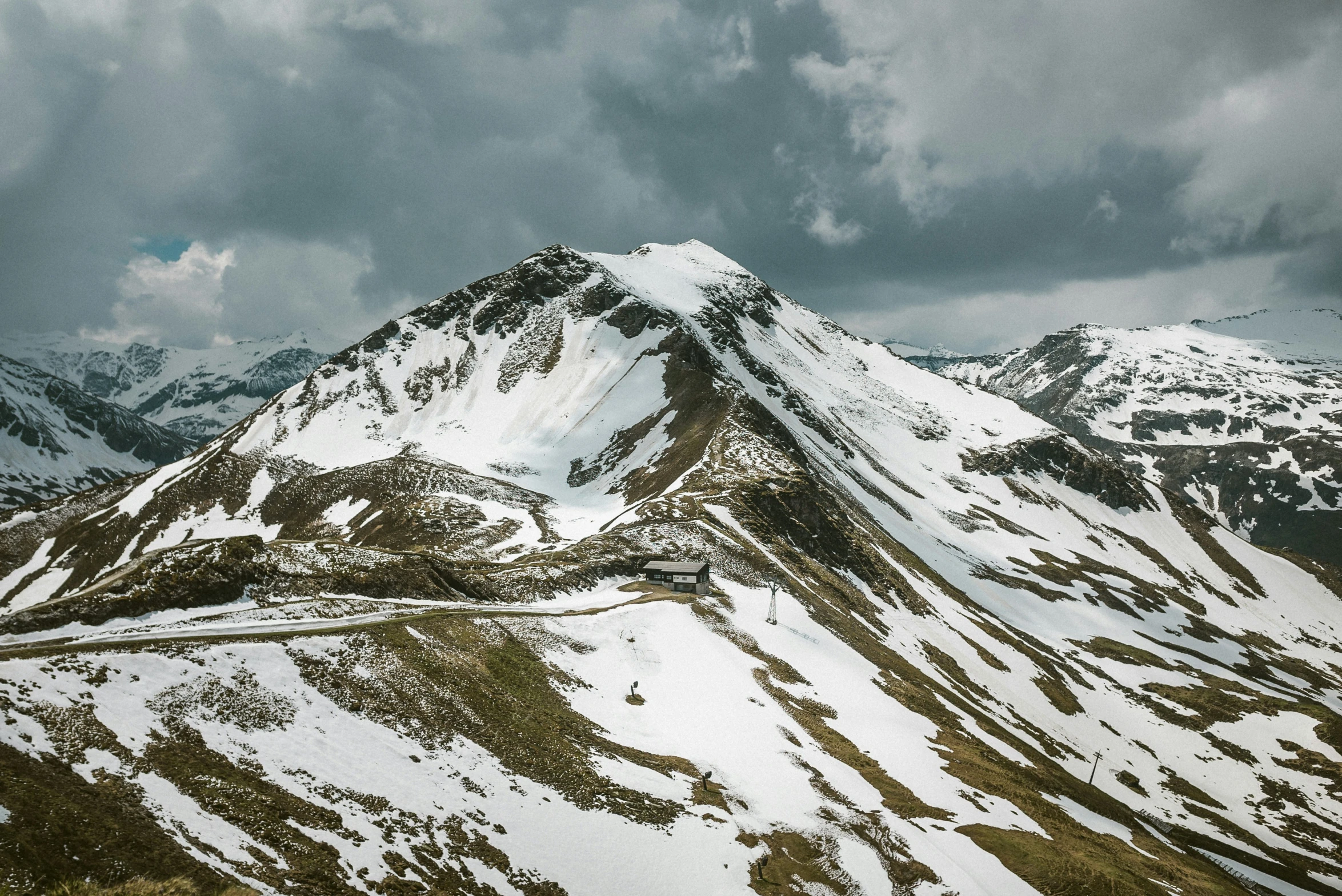 the snowy mountains and roads of a valley under stormy skies