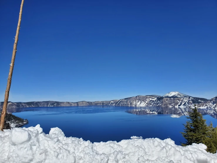 a mountain covered with snow next to a blue lake