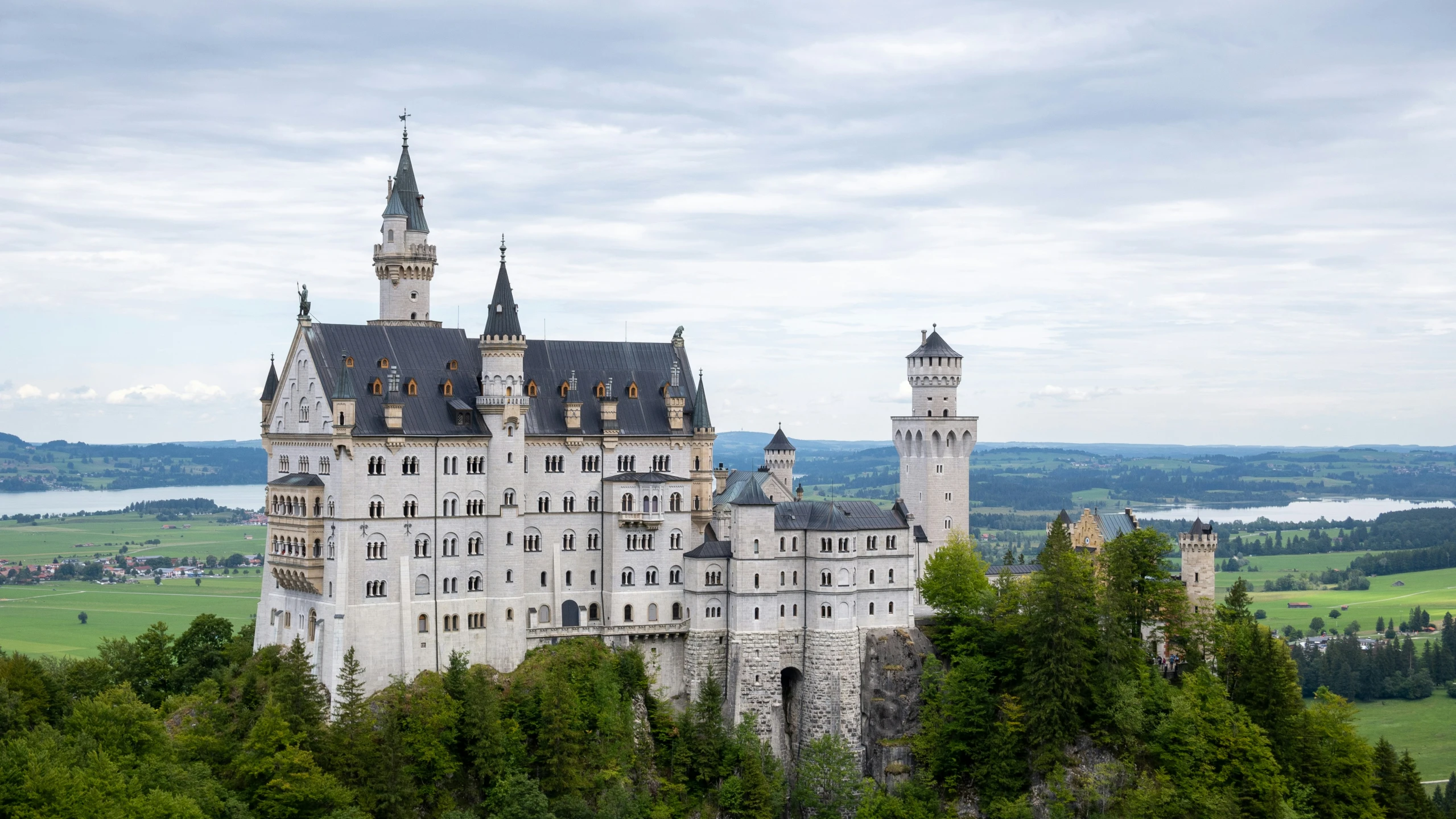 a castle with steeples stands on top of a hill