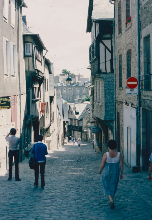 three people walking on the cobblestone of a street