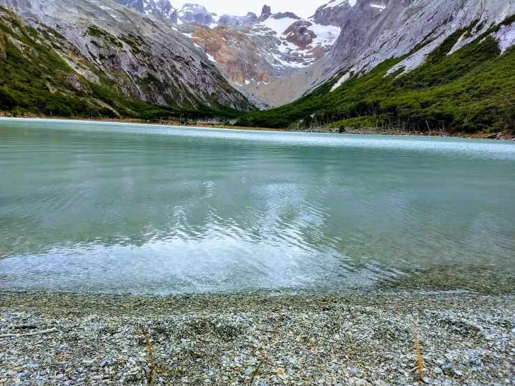 a pond surrounded by mountains near a forest