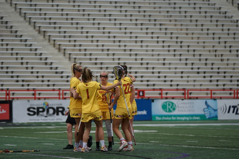 the girls lacrosse team huddle together on the field