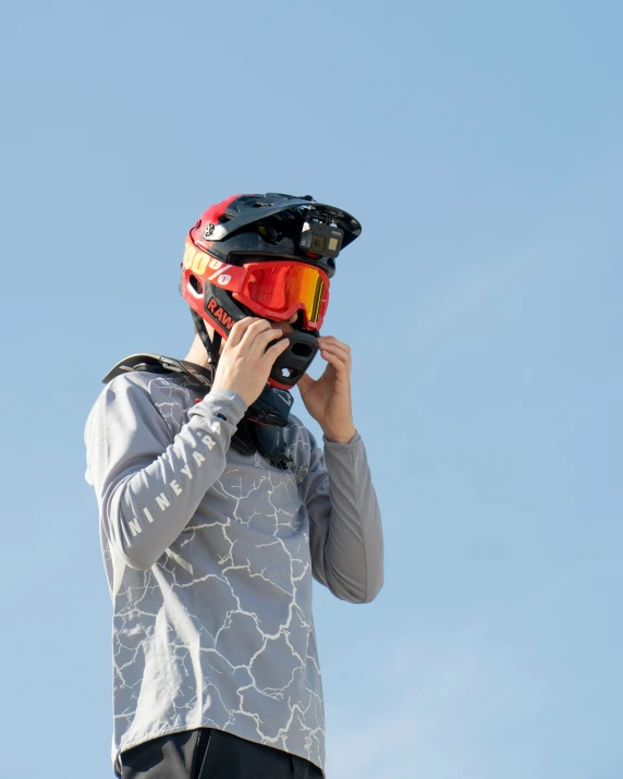 a man wearing helmet on the phone, wearing a pair of ski gloves
