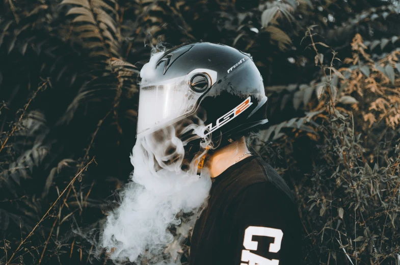 the back end of a person wearing a motorcycle helmet, near a bush