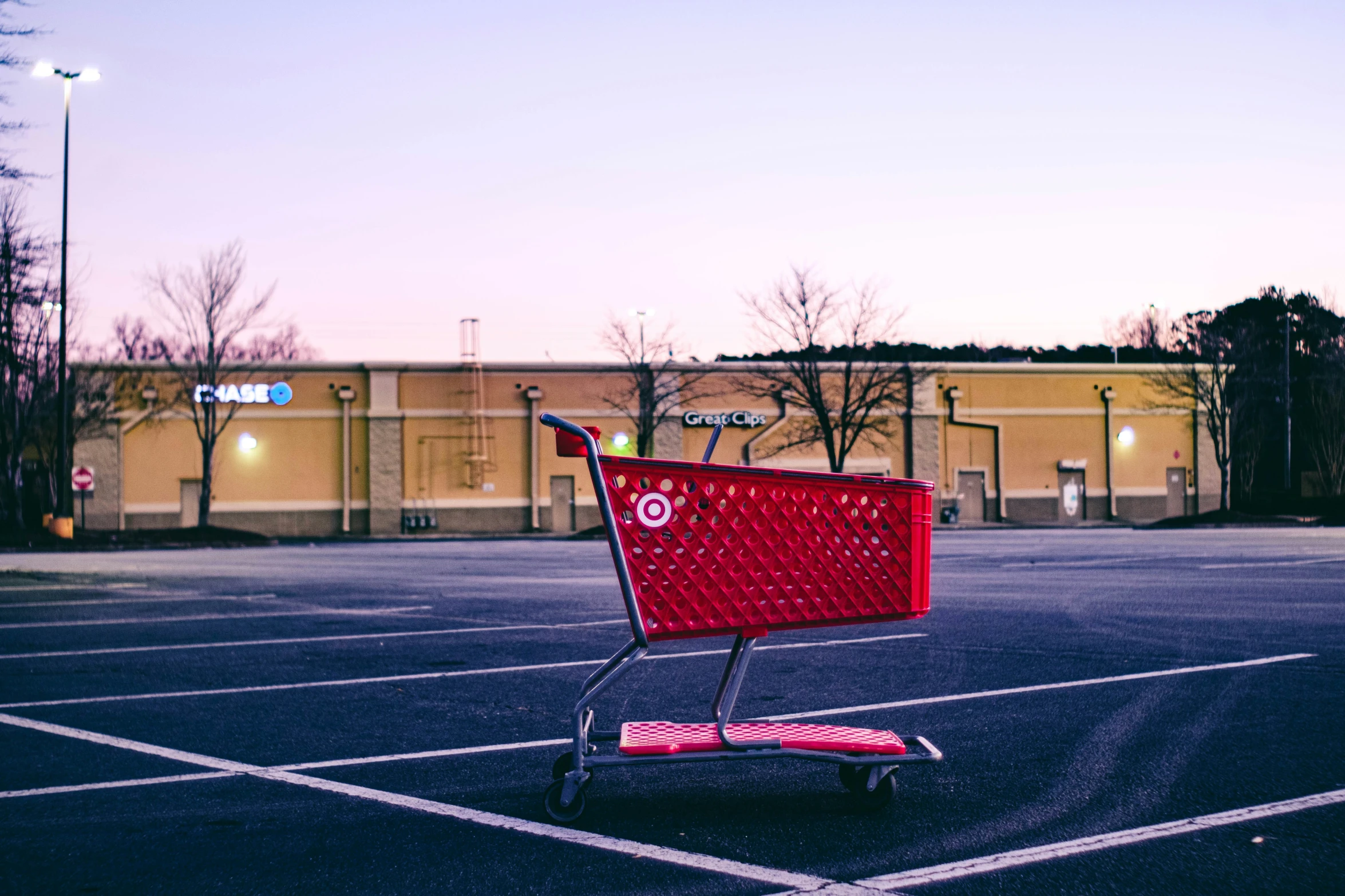 a red grocery cart in the middle of the parking lot