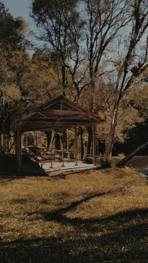 an empty gazebo sits in a field of dead grass