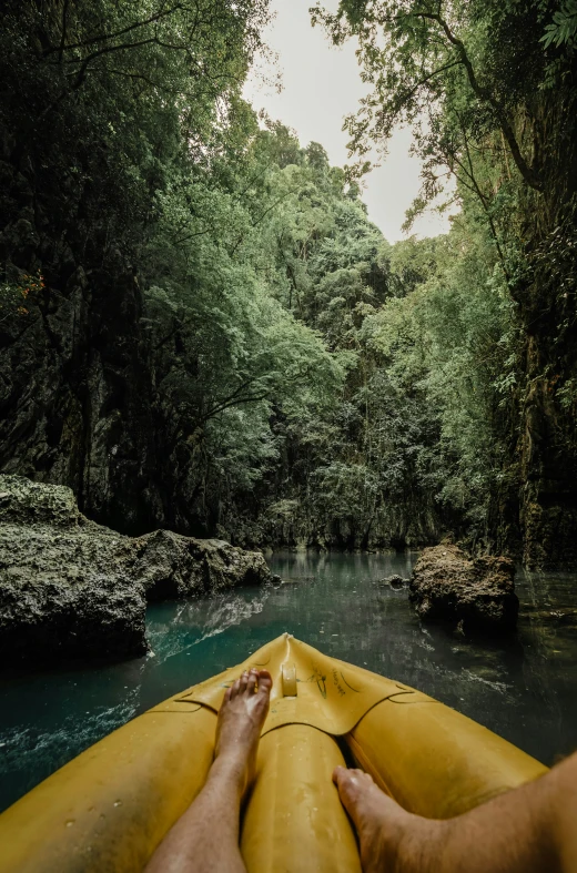 a man is paddling a yellow kayak down a stream