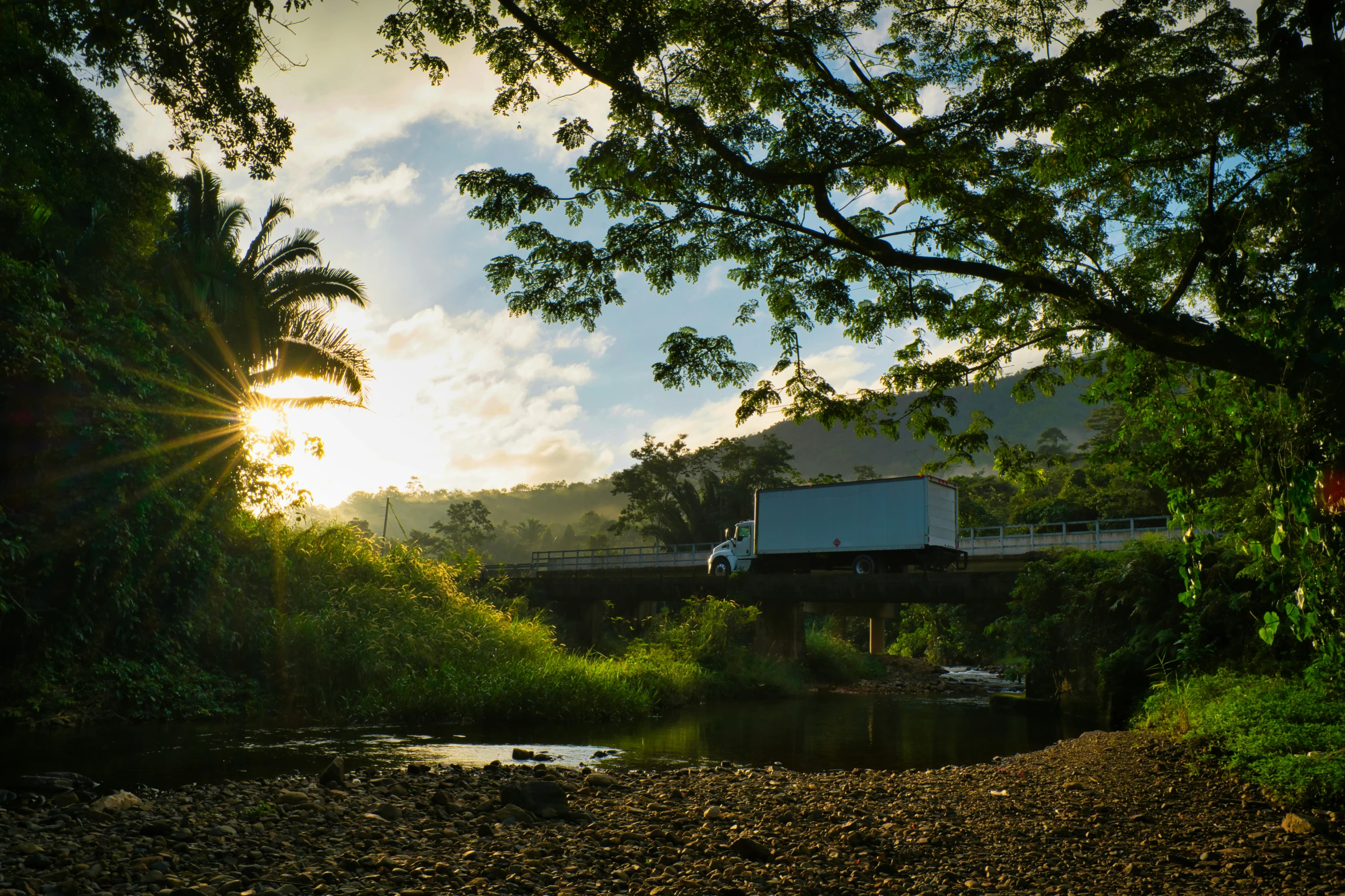 a truck driving along a river on a bridge