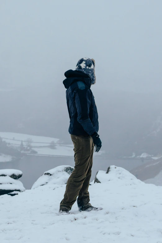 a man wearing a jacket and a hat stands on a snowy slope