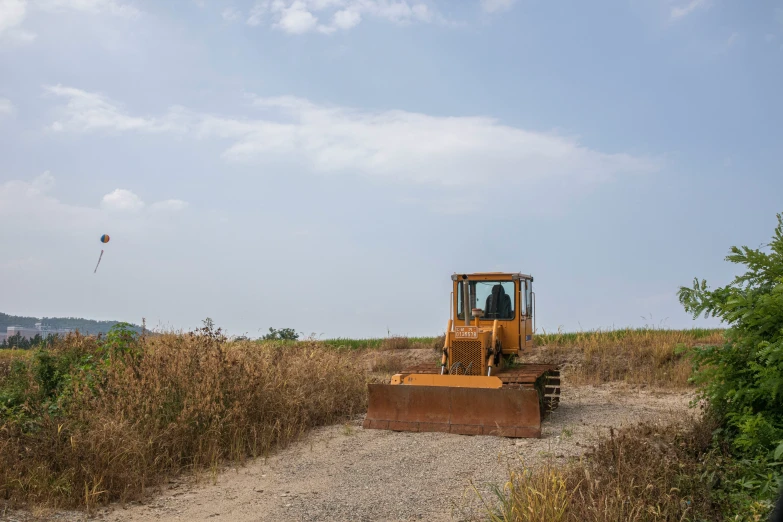 a bulldozer parked on a dirt road surrounded by brush
