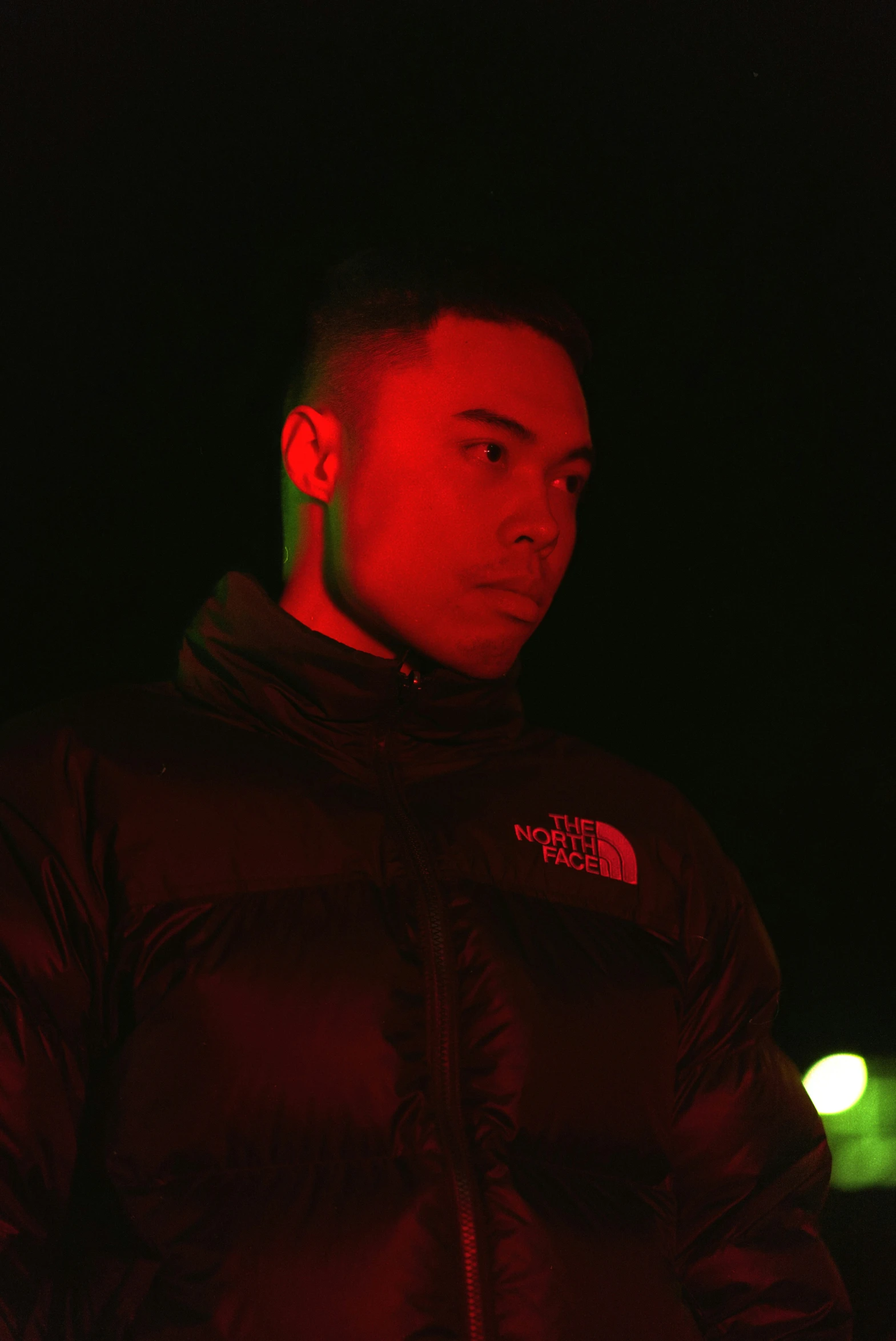 a man standing under the red light at night