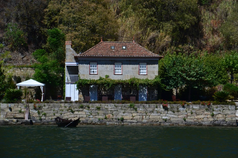 a house next to the water with trees around