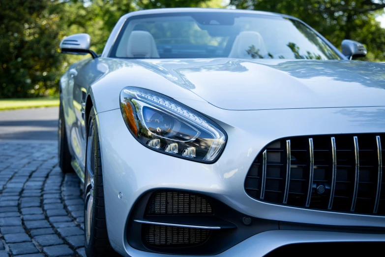 the front grille of a white mercedes sls coupe on brick driveway