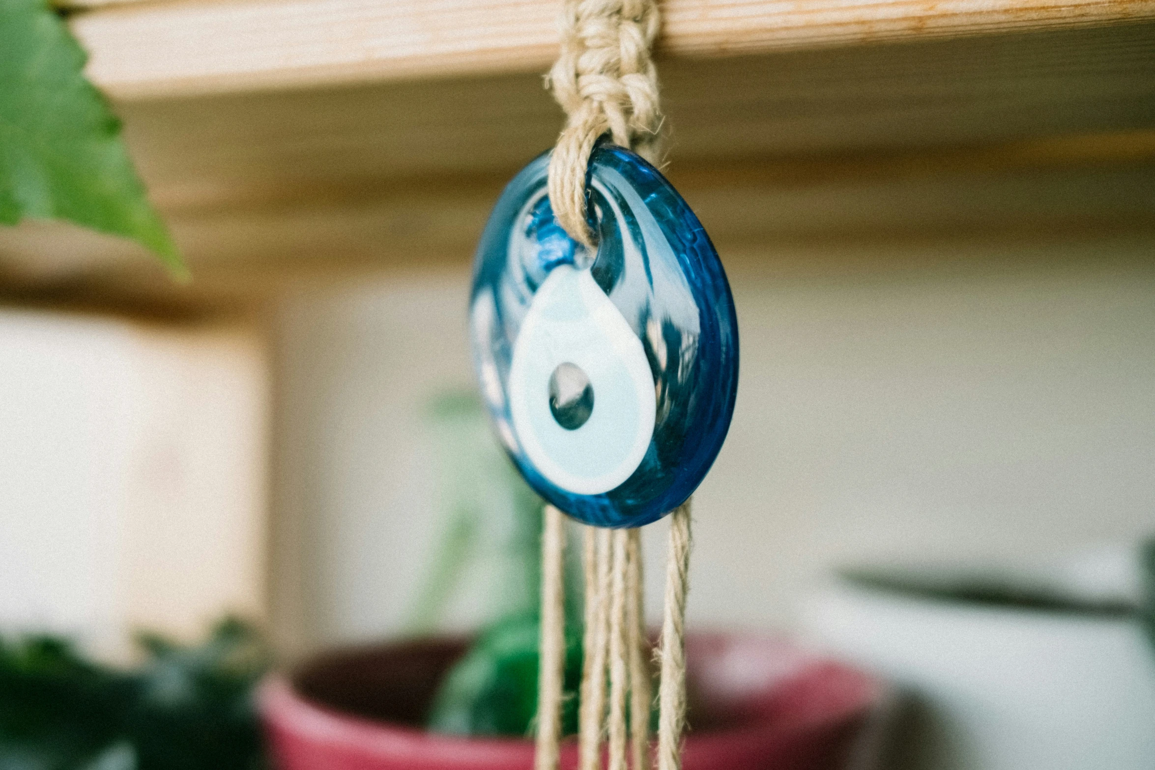 a wooden shelf with a plant and a paper roll hanging on a string