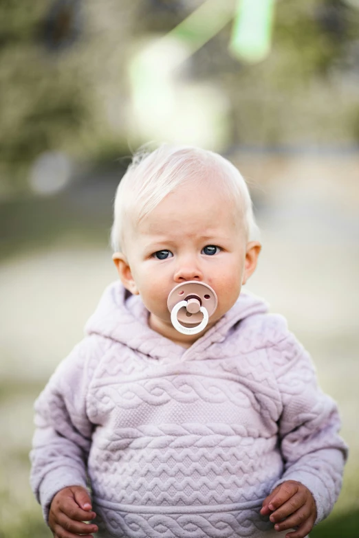 a baby wearing a pacifier is looking directly at the camera