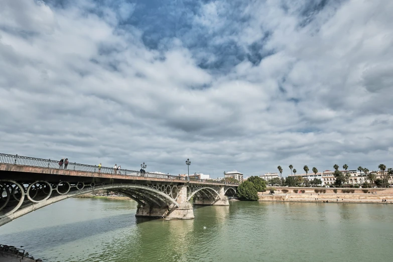 people on bikes crossing over a bridge that spans the width of a river