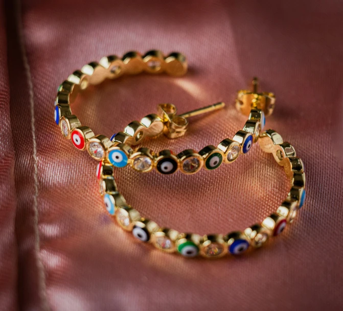 two colorfully decorated earrings with small diamonds