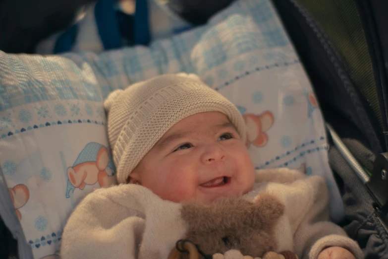 a little baby sitting in the stroller next to a teddy bear