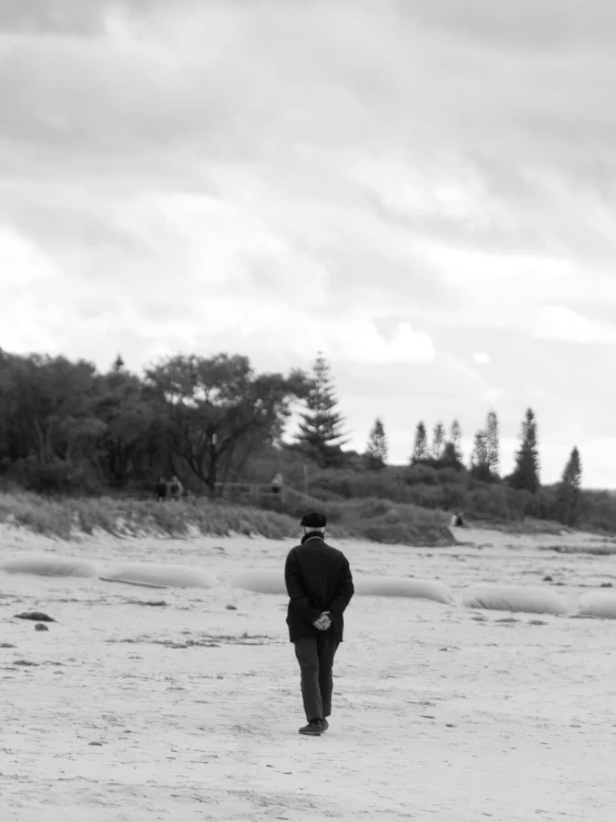 a man walking down a beach carrying a kite