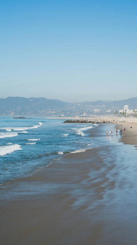 a group of people stand at the edge of the ocean on the beach