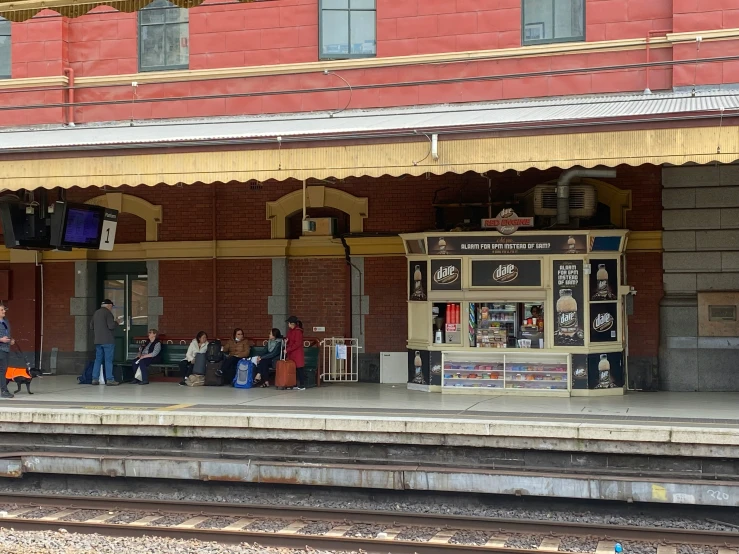 some people sitting at the platform of a train station