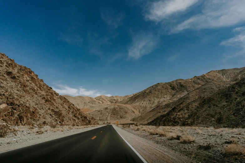 the back end of a car drives through an empty mountain pass