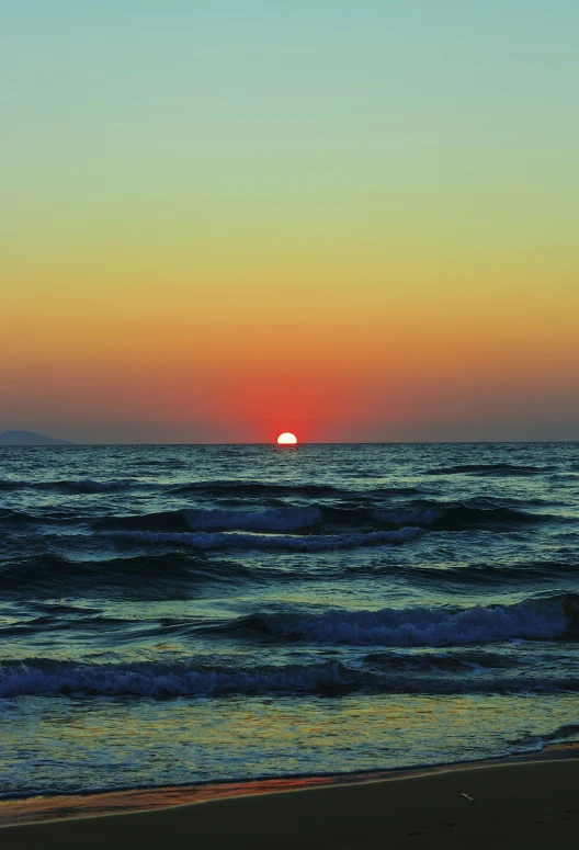 the sun is rising behind the horizon of the ocean