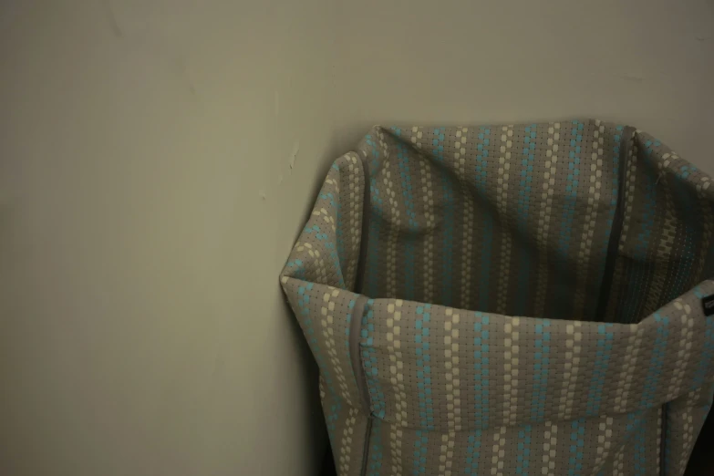 a seat pocket with fabric underneath it sitting against a wall