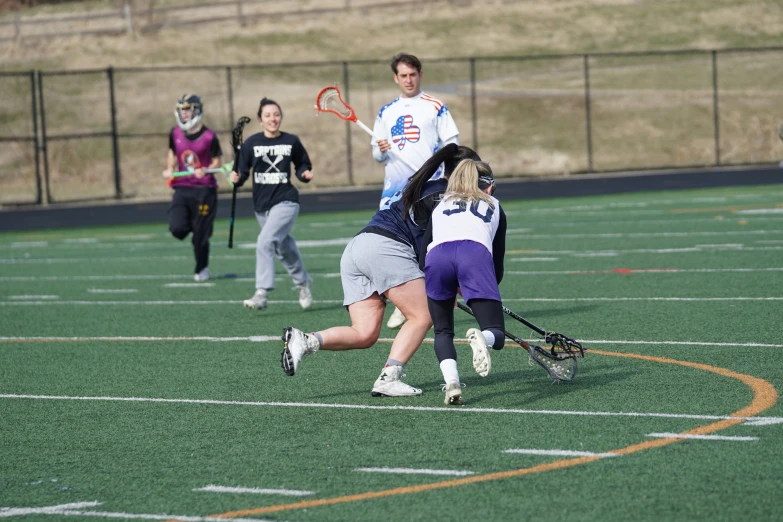 four girls playing a field hockey match on an open field