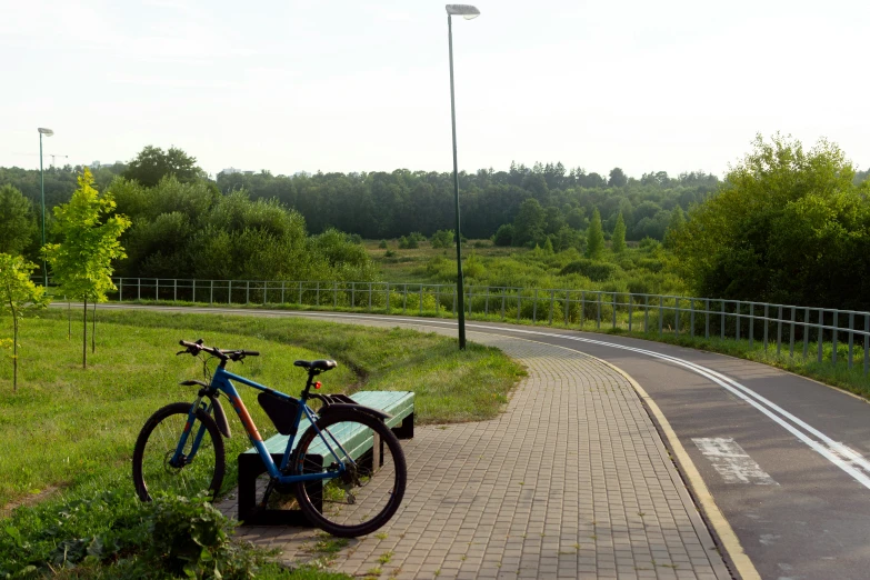 a bike sits next to a bench along a paved path