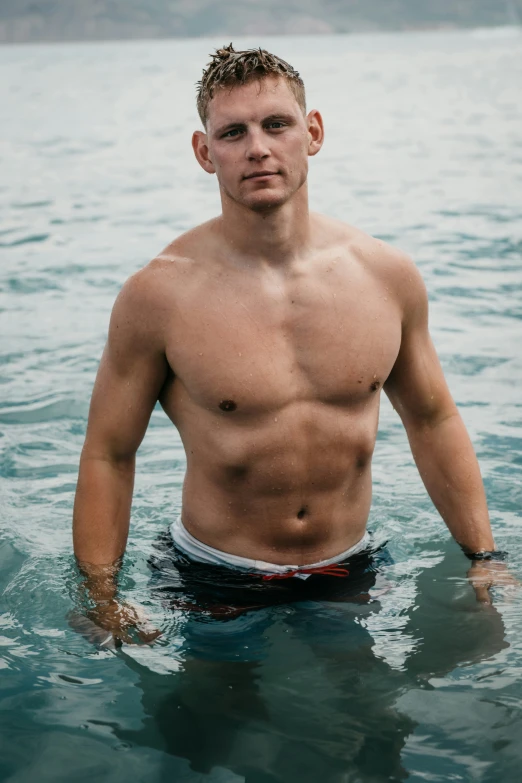the shirtless young man poses in the ocean