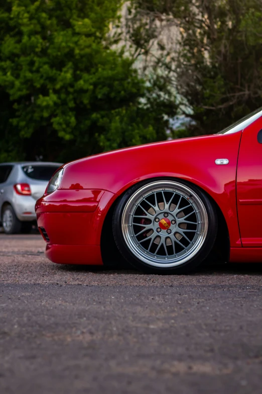 a red car parked in a lot next to other cars