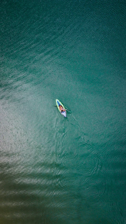 the person in the green kayak floats on the green water