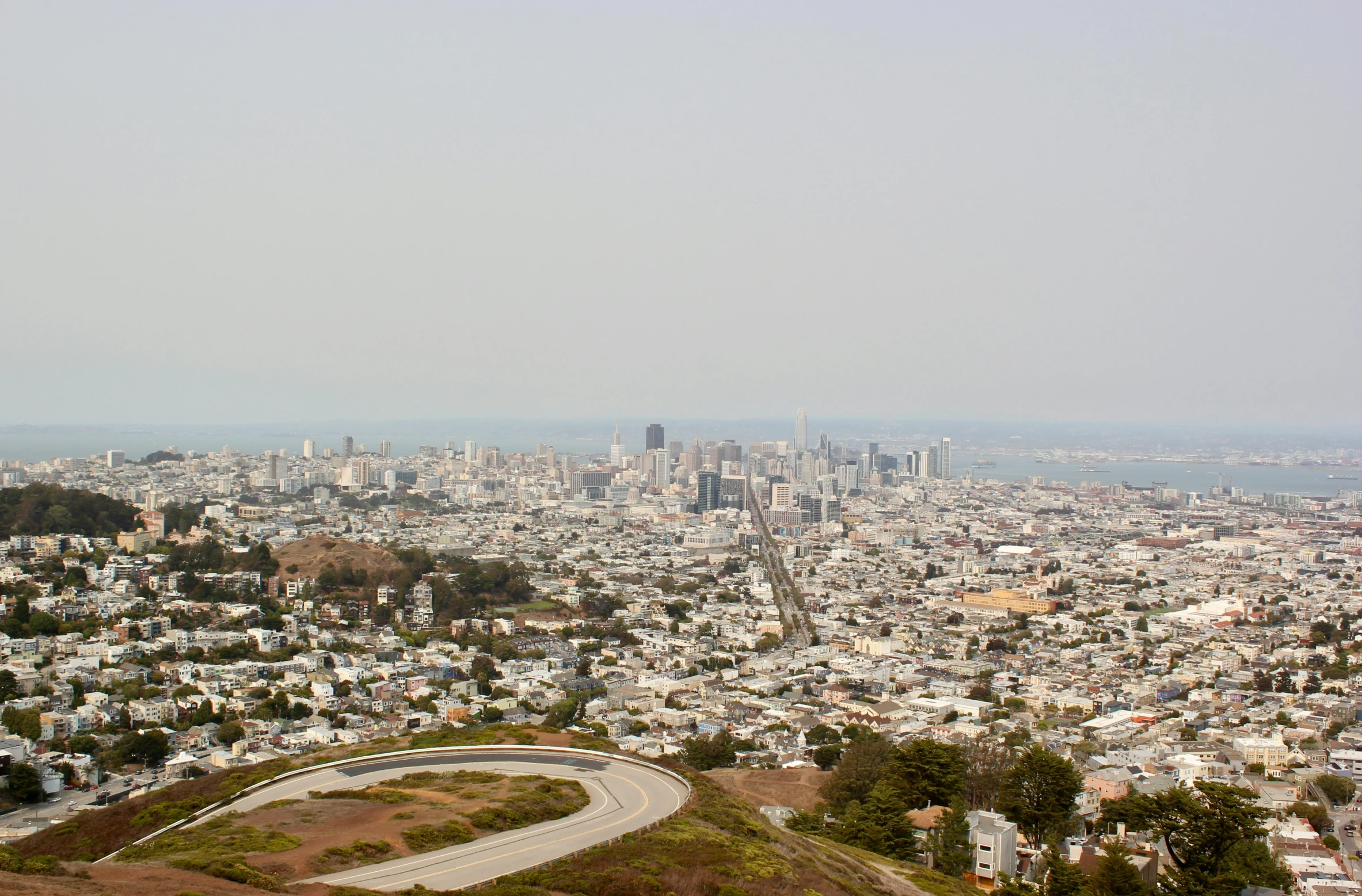 a city skyline with mountains and a curved road