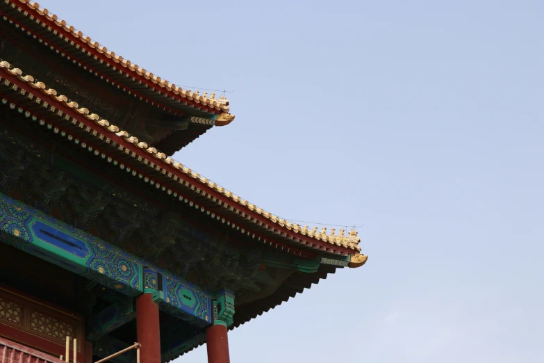 the roof top of a chinese building against a blue sky