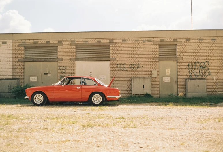 a vintage red sports car parked outside a building