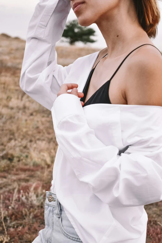 woman wearing jeans and top standing near dry grass