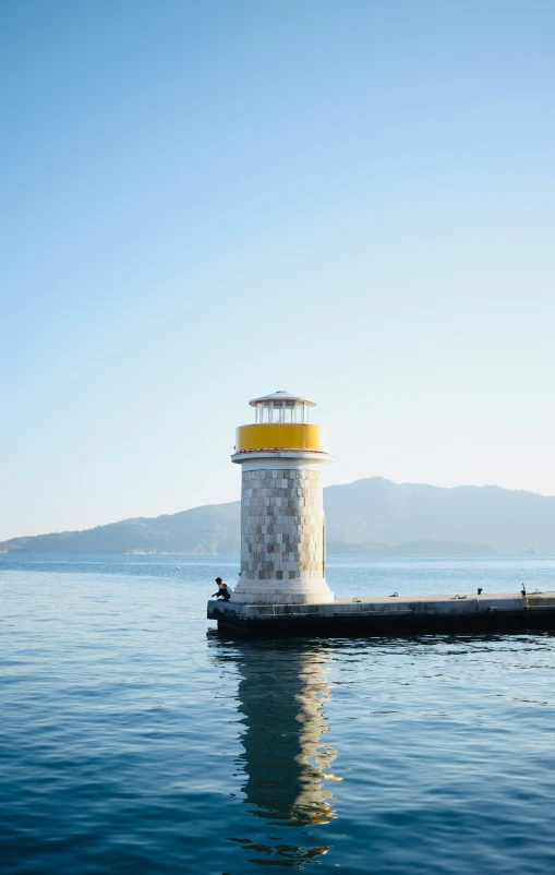 a small lighthouse with a yellow top is sitting out in the water