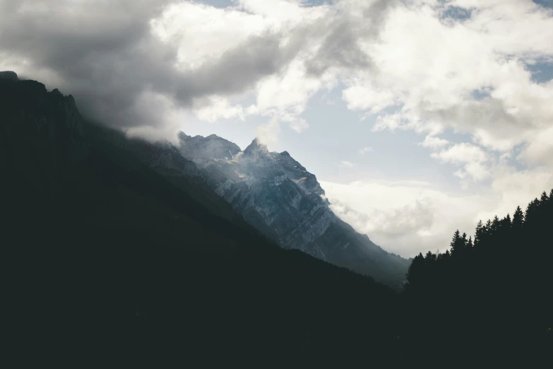 the clouds are over the trees and mountains